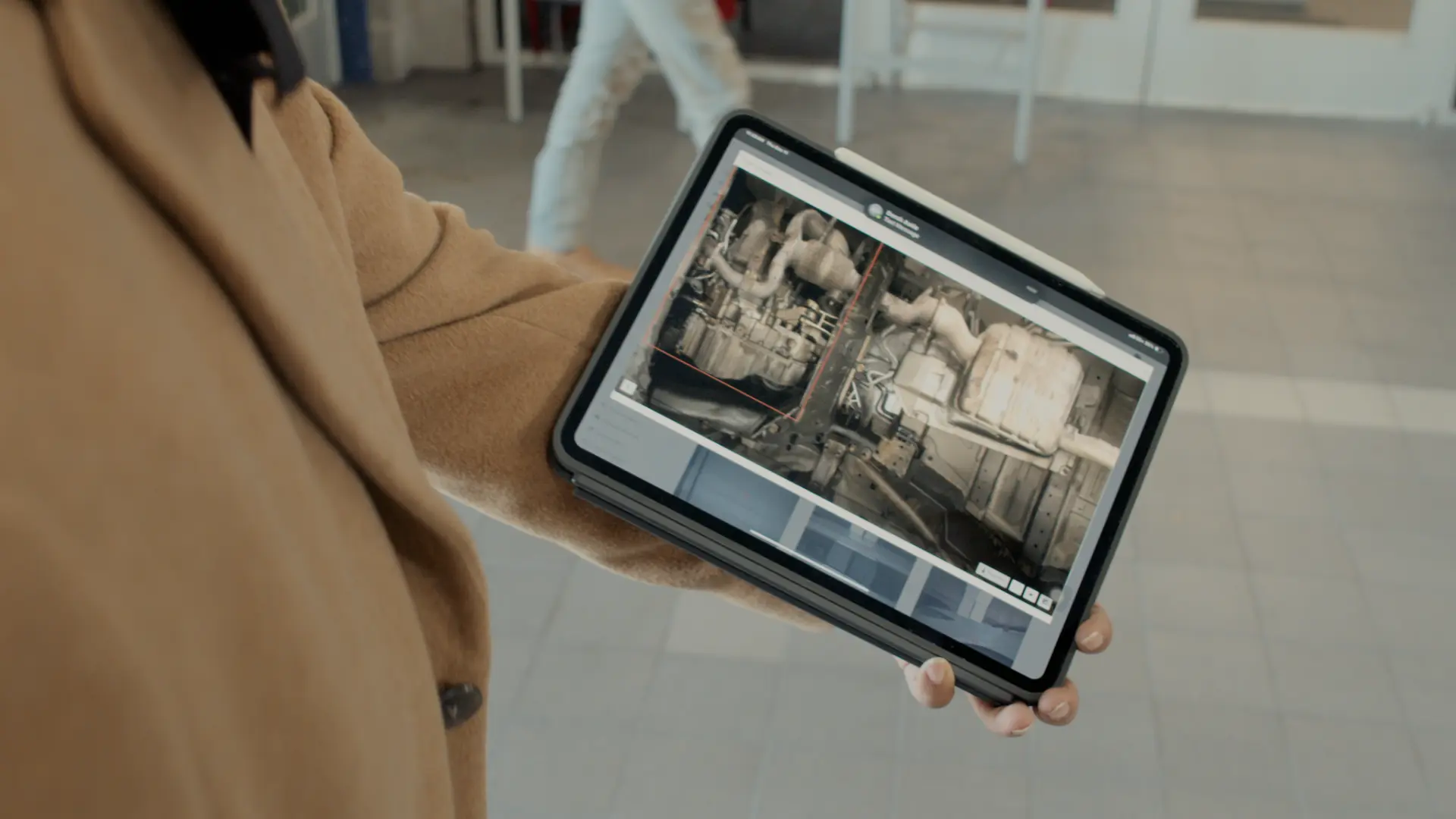 Serviceberater zeigt einen UVeye-Unterbodenbericht auf dem Tablet